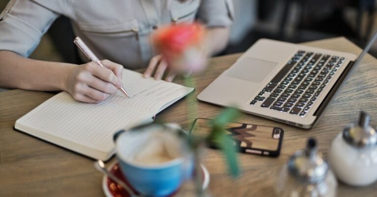 Content Marketing - Person Writing On A Notebook Beside Macbook