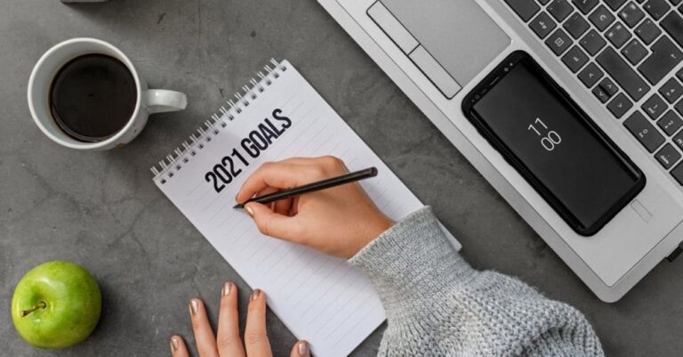 Resolution - Top view crop anonymous female in sweater writing down goals for 2021 year in notebook while sitting at desk with laptop and cup of coffee